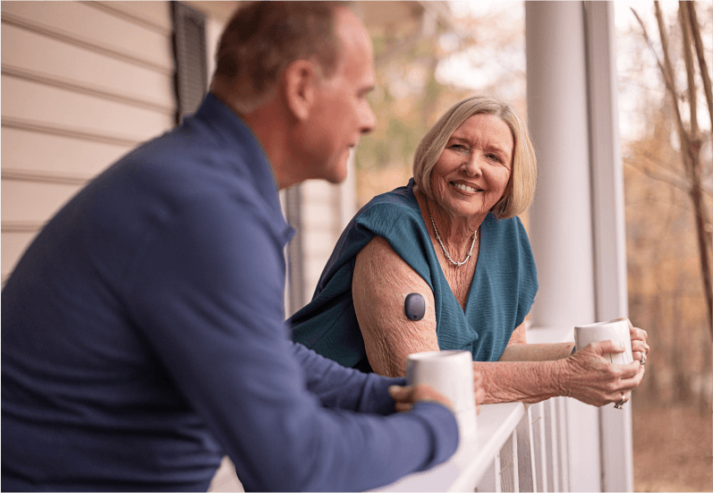 Eversense CGM device user talks with man on outdoor patio