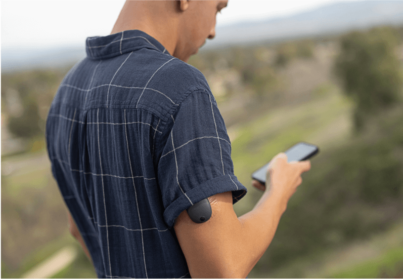 Eversense user standing outside using a smartphone to monitor his glucose patterns 